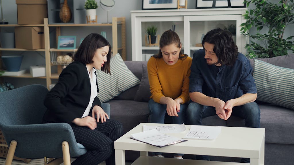 A couple consults with a real estate agent in a comfortable home setting.