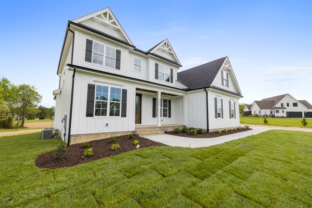 Charming white two-story house with green lawn, showcasing modern architecture and spacious design.